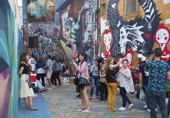 turistas andando em rua grafitada no bairro Vila Madalena